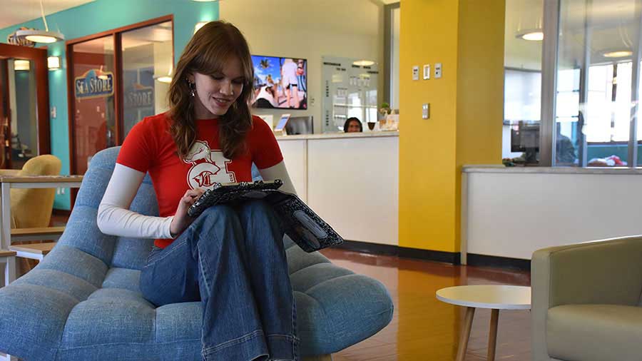 A CSUCI student seated holding a tablet